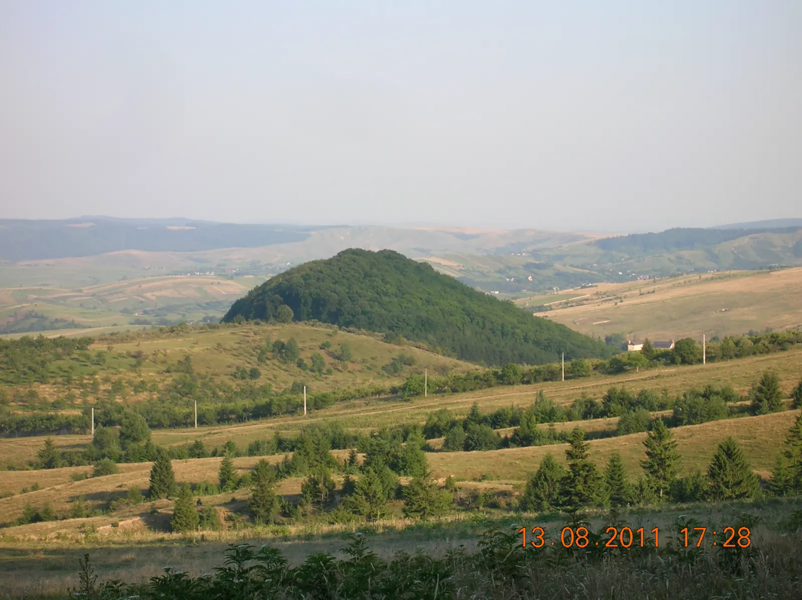 Un deal împădurit deasupra unei văi deschise din parc